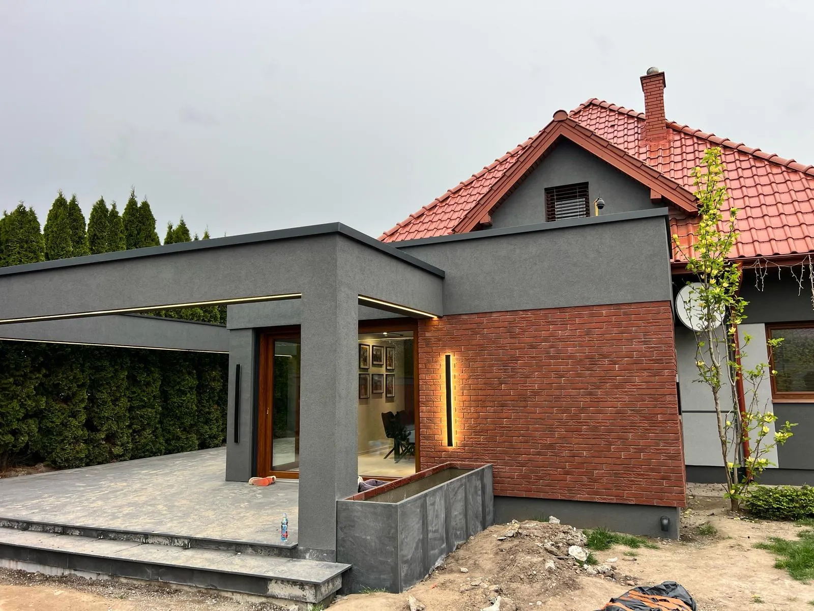 Zadaszenie tarasu w grafitowym tynku przy ceglanej ścianie