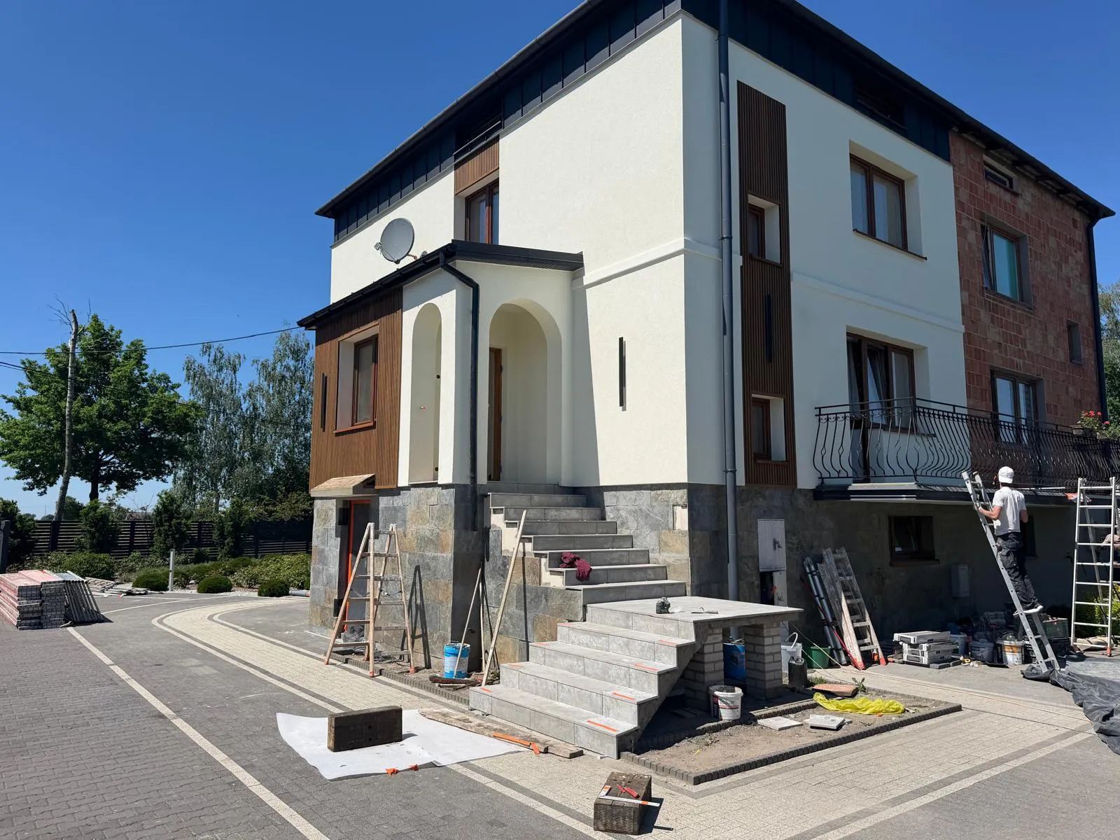 Dom piętrowy po zmianie elewacji, widok na schody wejściowe i balkon